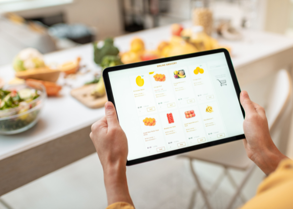 Hands holding tablet, display has grocery icons for ordering online