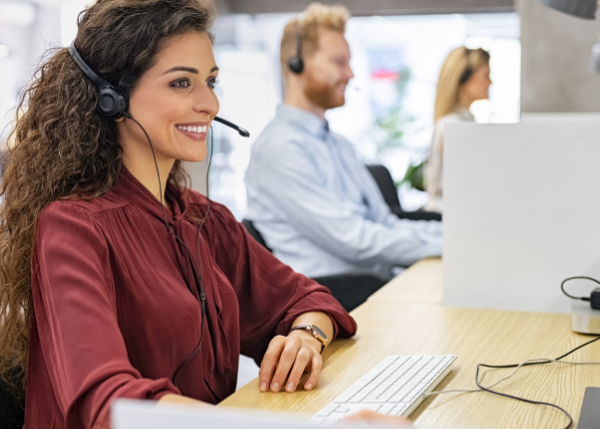 Woman with headset on at computer in a call center.